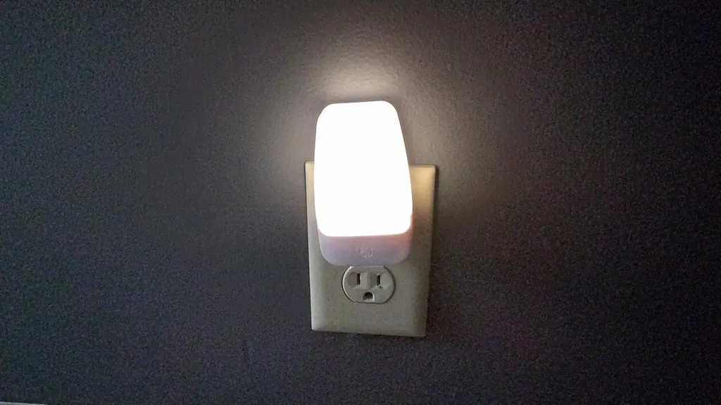 Une petite veilleuse branchée sur une prise diffuse une lumière douce dans l'obscurité