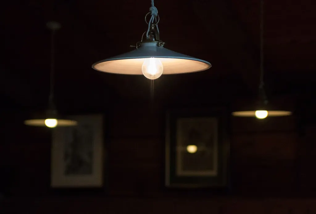 Des suspensions diffusent une lumière chaude et tamisée dans une pièce plongée dans la pénombre du soir
