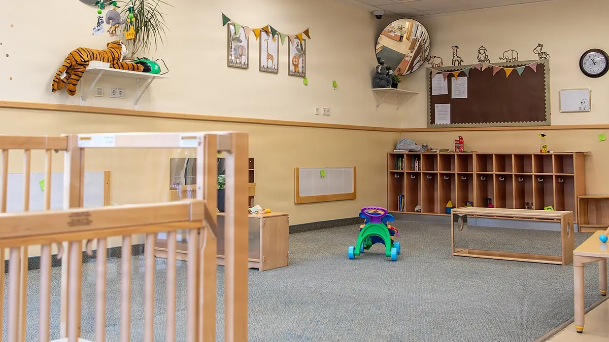 Une salle de crèche vide et rangée, avec des lits à barreaux en bois, des étagères et des jouets