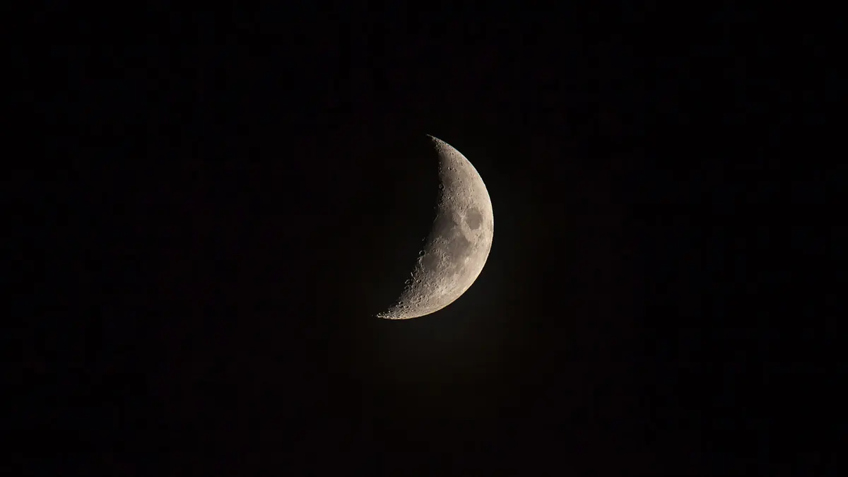 Un fin croissant de lune éclairé dans un ciel nocturne d'un noir profond